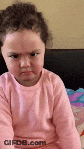 A Little Girl Wearing A Pink Shirt Is Making A Funny Face GIF