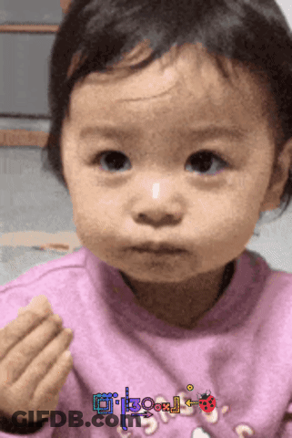 A Little Girl Wearing A Pink Sweater With A Ladybug On It Looks At The Camera GIF