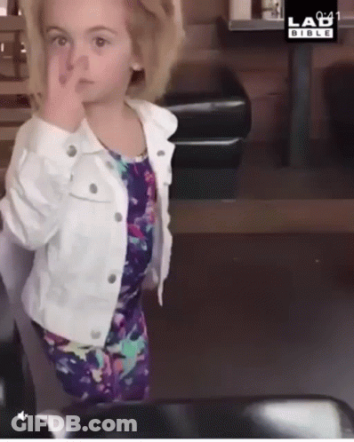 A Little Girl Wearing A White Jacket And A Purple Dress Is Giving The Middle Finger GIF
