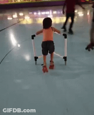 A Little Girl Wearing Roller Skates Is Walking On A Rink GIF