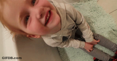 A Little Girl Wearing Striped Pants And A Shirt With A Bow On It GIF