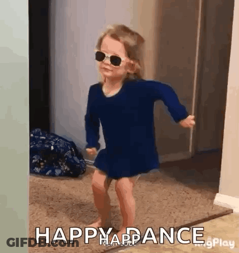 A Little Girl Wearing Sunglasses And A Blue Dress Is Dancing In A Hallway . GIF