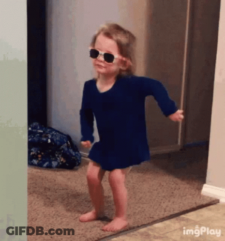 A Little Girl Wearing Sunglasses And A Blue Dress Is Dancing On The Floor . GIF