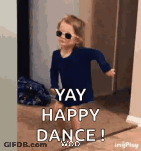 A Little Girl Wearing Sunglasses And A Blue Shirt Is Dancing In A Hallway . GIF