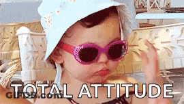 A Little Girl Wearing Sunglasses And A Hat With The Words `` Total Attitude '' Written Above Her . GIF