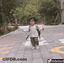 A Little Girl With A Backpack Is Walking Down A Brick Road .. GIF