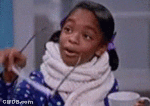 A Little Girl With A Scarf Around Her Neck Is Holding A Cup Of Coffee . GIF
