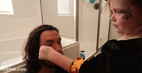 A Little Girl With A Spider Web Painted On Her Face Is Applying Makeup To A Man 'S Face GIF