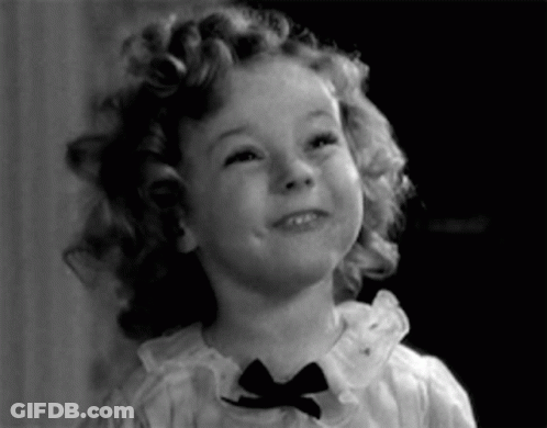 A Little Girl With Curly Hair Is Wearing A Bow Tie GIF