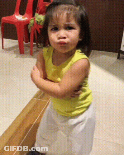 A Little Girl With Her Arms Crossed Making A Face GIF