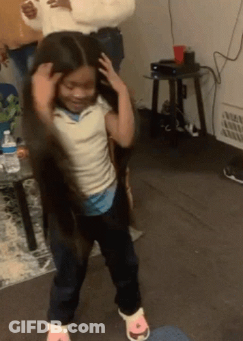A Little Girl With Long Hair Is Dancing In A Living Room With A Woman Holding Her Hair . GIF