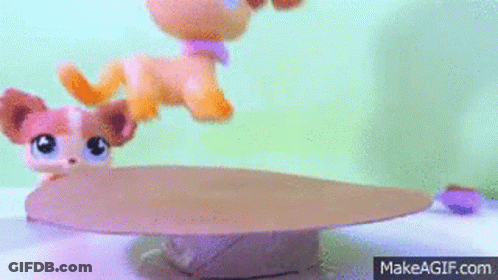 A Littlest Pet Shop Dog Is Standing On Top Of A Cardboard Box On A Table . GIF