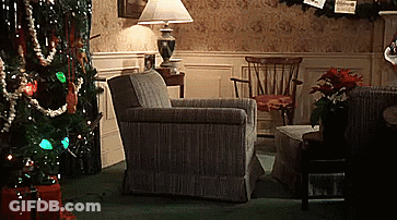 A Living Room Decorated For Christmas With A Chair A Lamp And A Christmas Tree GIF