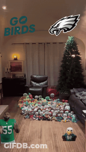 A Living Room With A Christmas Tree And Stuffed Animals And The Words Go Birds On The Ceiling GIF