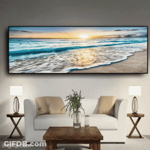 A Living Room With A Couch And A Table With A Picture Of A Beach On The Wall GIF
