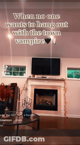 A Living Room With A Fireplace And A Tv With A Caption That Says When No One Wants To Hang Out With The Town Vampire GIF