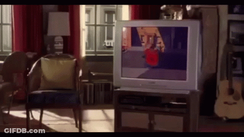 A Living Room With A Television On A Stand And A Guitar GIF