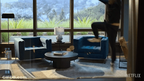 A Living Room With Blue Chairs And A Coffee Table With A Netflix Logo In The Corner GIF