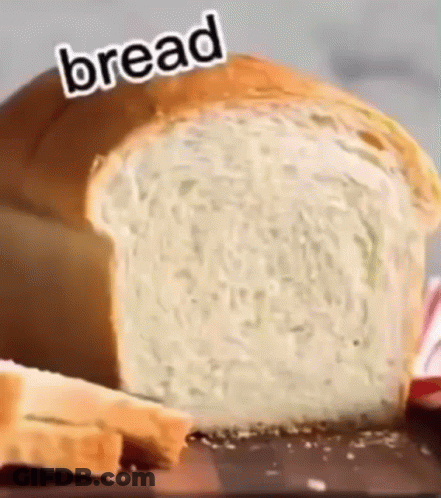 A Loaf Of Bread Is Sitting On Top Of A Wooden Table . GIF