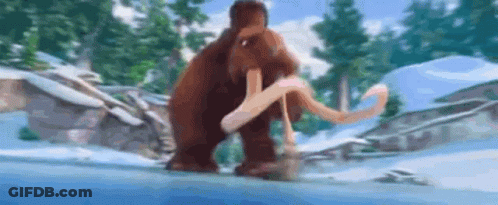 A Mammoth Is Walking Through The Snow In A Snowy Forest . GIF