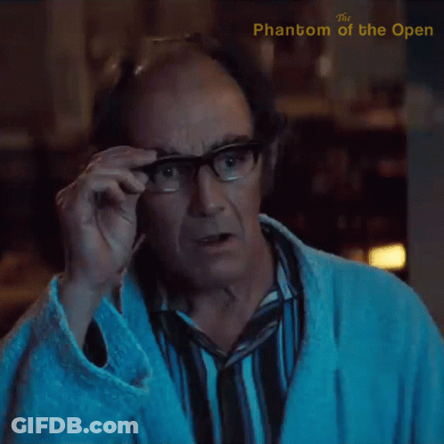 A Man Adjusts His Glasses With The Phantom Of The Open Written On The Bottom GIF