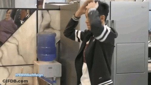 A Man Adjusts His Hair In Front Of A Water Dispenser With The Hashtag #Pbbm8keltreign GIF
