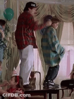 A Man And A Boy Are Dancing In A Living Room . GIF