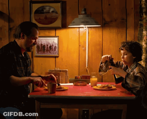 A Man And A Boy Are Sitting At A Table With Plates Of Food GIF