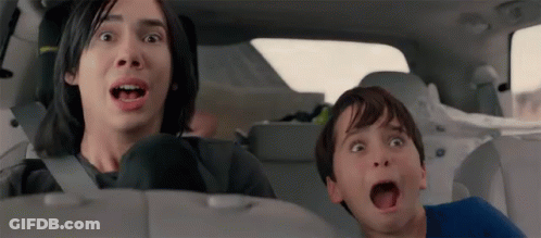 A Man And A Boy Are Sitting In The Back Seat Of A Car Making Funny Faces . GIF