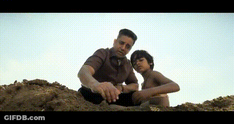 A Man And A Boy Are Sitting On Top Of A Hill Playing With Sand . GIF