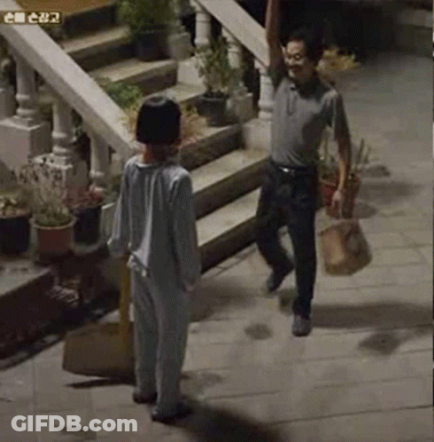 A Man And A Boy Are Standing On A Sidewalk Next To Stairs . GIF