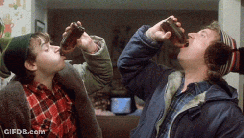 A Man And A Boy Drinking From Bottles In A Living Room GIF