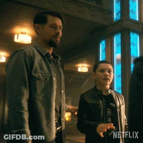 A Man And A Boy Standing Next To Each Other With A Netflix Logo Behind Them GIF