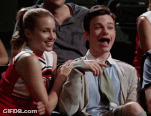 A Man And A Cheerleader Are Sitting Next To Each Other In A Crowd GIF