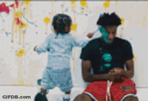 A Man And A Child Are Playing With Paint On A White Wall . GIF