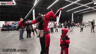 A Man And A Child Dressed In Deadpool Costumes Are Dancing In A Crowded Room . GIF
