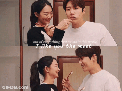 A Man And A Woman Are Brushing Their Teeth In A Bathroom GIF