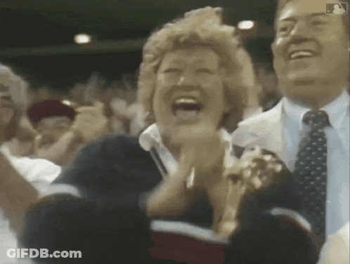 A Man And A Woman Are Clapping In A Crowd With A Mlb Logo In The Corner GIF