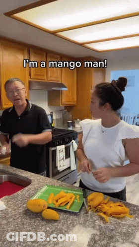 A Man And A Woman Are Cutting Mangoes In A Kitchen And The Man Is Saying I 'M A Mango Man . GIF