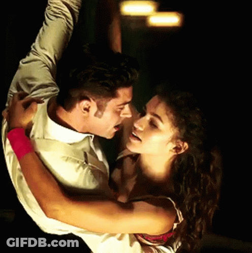 A Man And A Woman Are Dancing And The Woman Has A Pink Wristband GIF