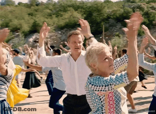 A Man And A Woman Are Dancing In A Crowd With Their Arms In The Air . GIF