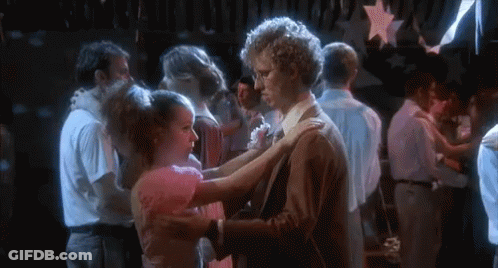 A Man And A Woman Are Dancing In A Crowded Room At A Party . GIF