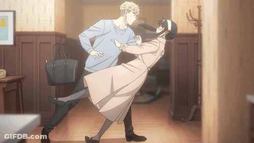 A Man And A Woman Are Dancing In A Hallway With A Purse GIF
