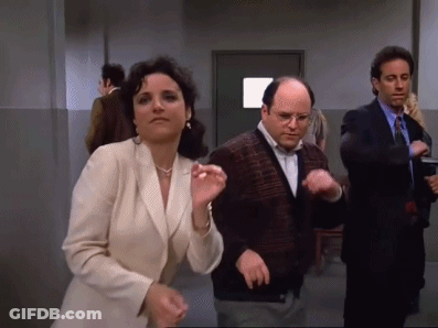 A Man And A Woman Are Dancing In A Hallway With Other People . GIF