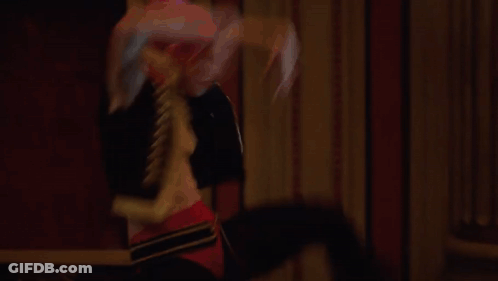 A Man And A Woman Are Dancing In A Large Hallway GIF