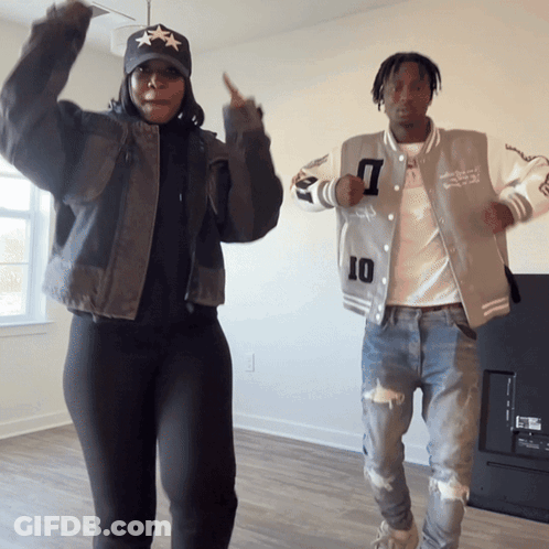 A Man And A Woman Are Dancing In A Living Room And The Man Is Wearing A Jacket With The Number 10 On It GIF
