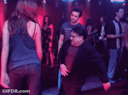 A Man And A Woman Are Dancing In A Nightclub . GIF