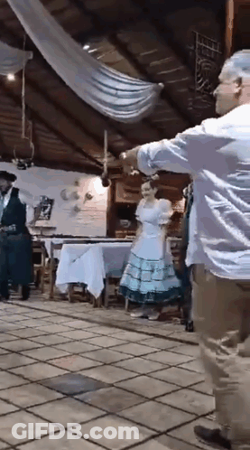 A Man And A Woman Are Dancing In A Room While A Man Plays A Guitar . GIF