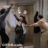 A Man And A Woman Are Dancing In A Room While A Woman Holds Her Hands Up In The Air . GIF
