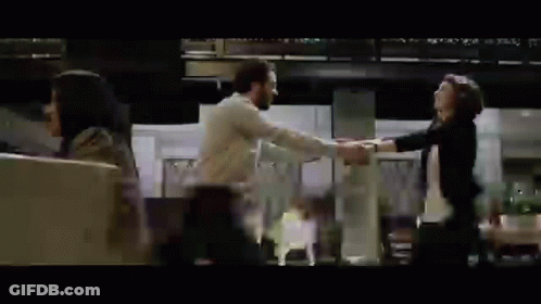 A Man And A Woman Are Dancing In A Room While A Woman Looks On . GIF